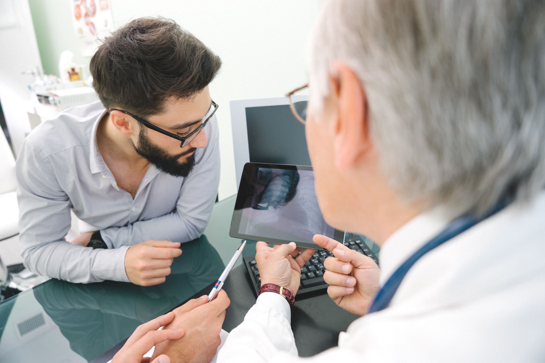 Arzt, welcher dem Patienten Röntgenbilder mithilfe einer digitalen Gesundheitsanwendung zeigt
