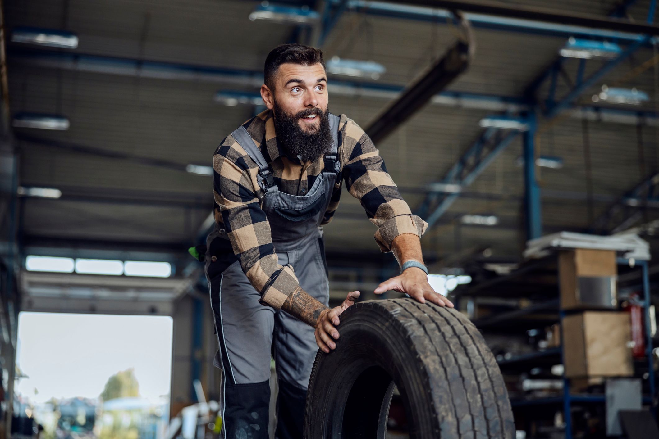Mechaniker rollt einen Reifen durch eine Werkstatt