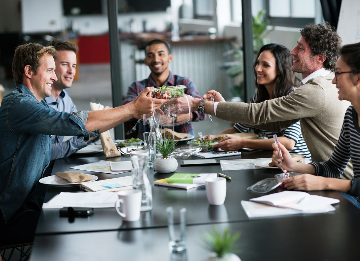 Mitarbeiter, welche in der Pause zusammen im Unternehmen am Tisch sitzen und essen