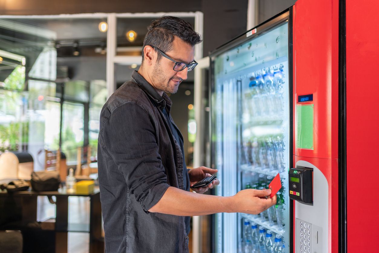 Mitarbeiter, der sich an einem Automaten etwas zu trinken kauft