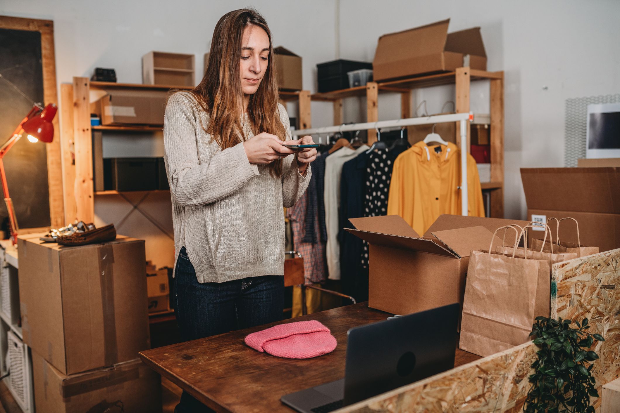 Junge Frau, welche mit ihrem Smartphone Kleidungsstücke fotografiert