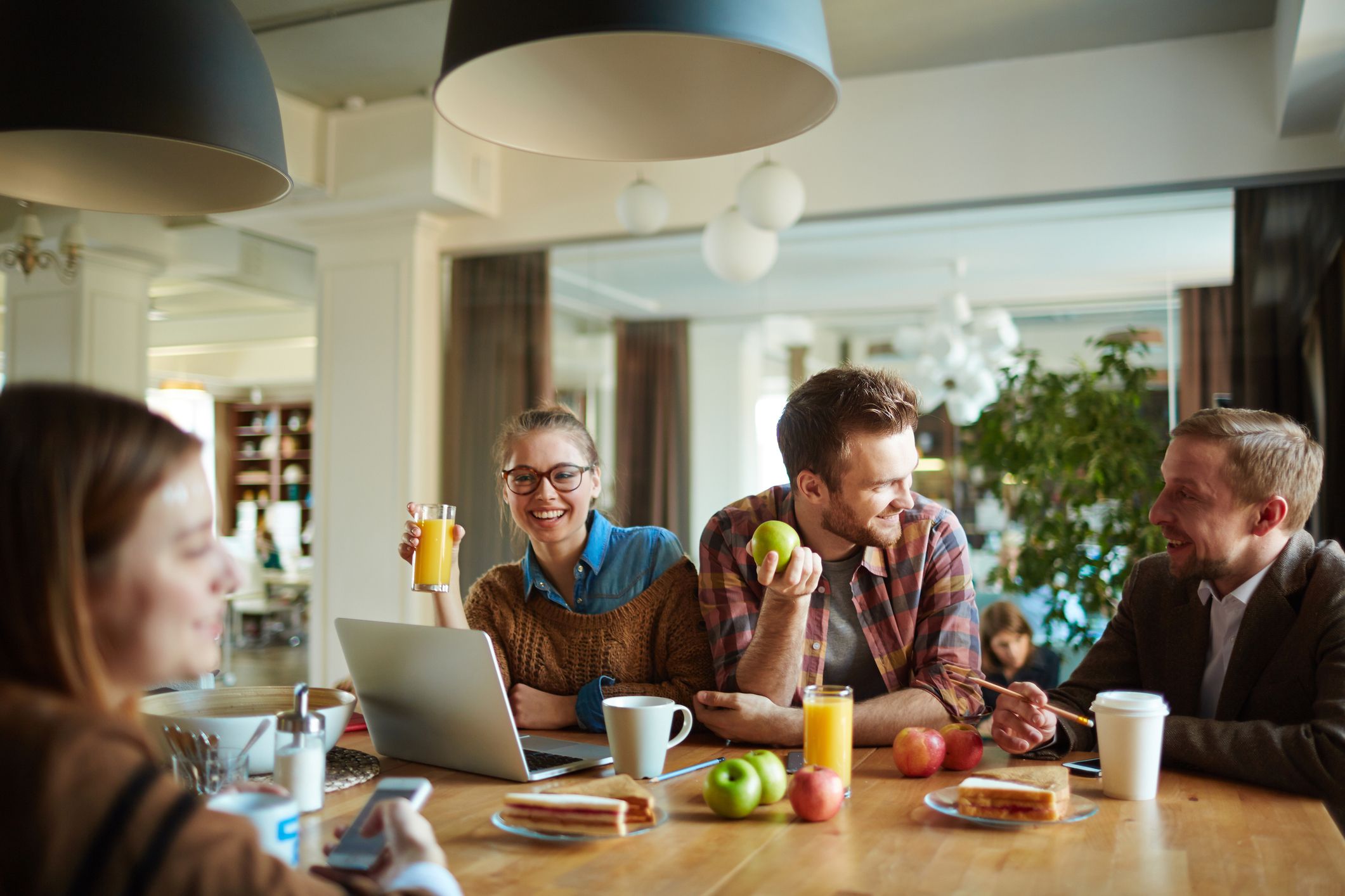 Lachende Menschen, die Obst und Säfte zusammen am Tisch essen und trinken